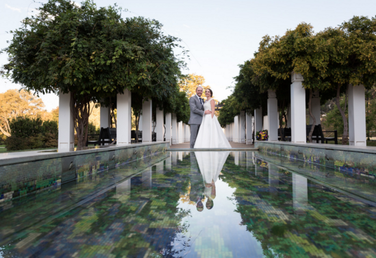 Bride and groom posing in front of concrete pond